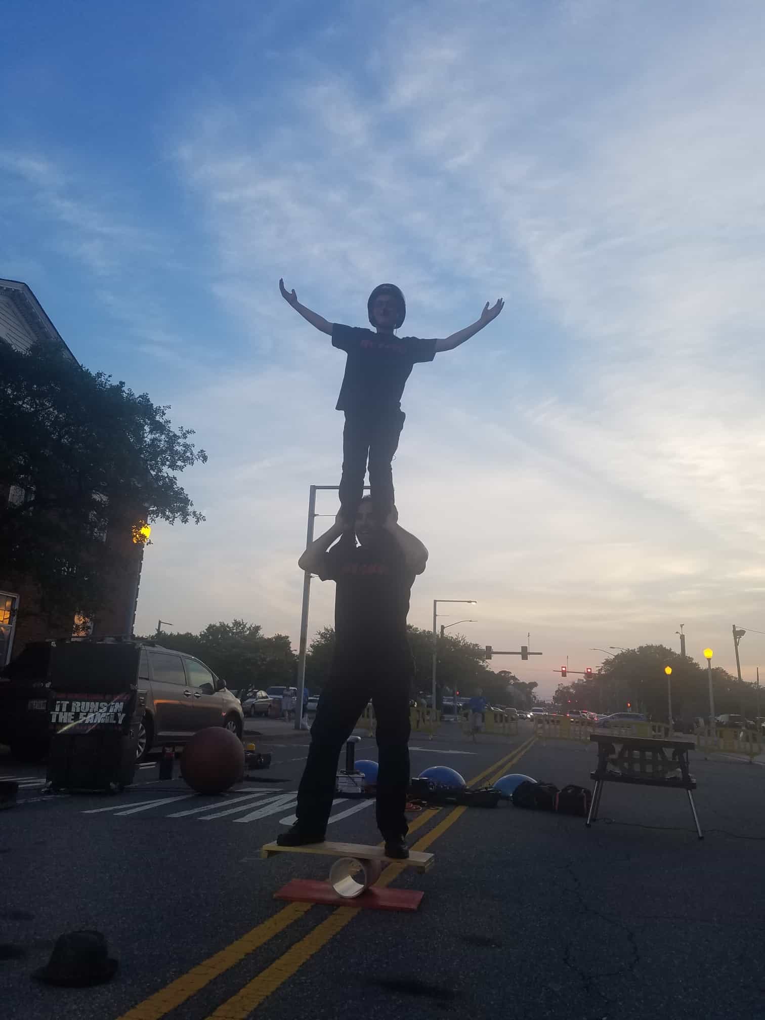 A man standing on top of another person balancing.