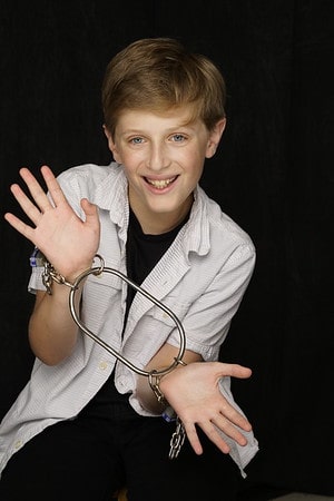 A young boy wearing a white lab coat and holding a stethoscope.