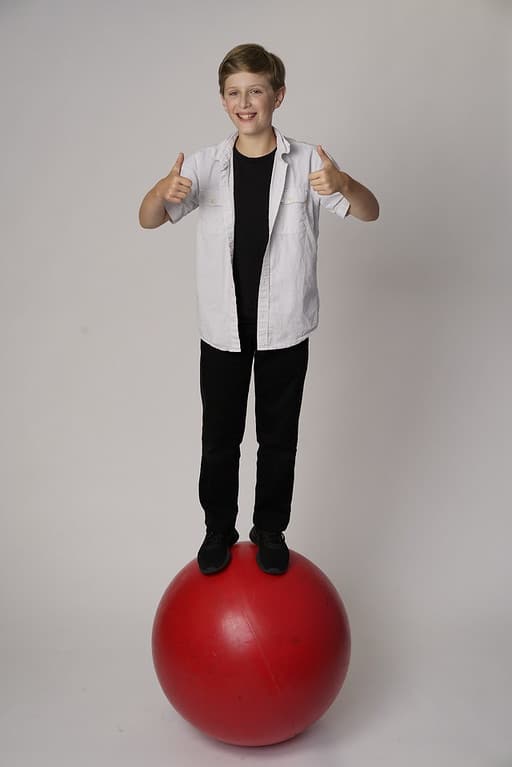 A man standing on top of a ball wearing a white shirt and tie.