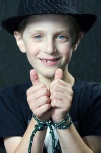 A young boy wearing a cowboy hat and holding his hands in front of the camera.