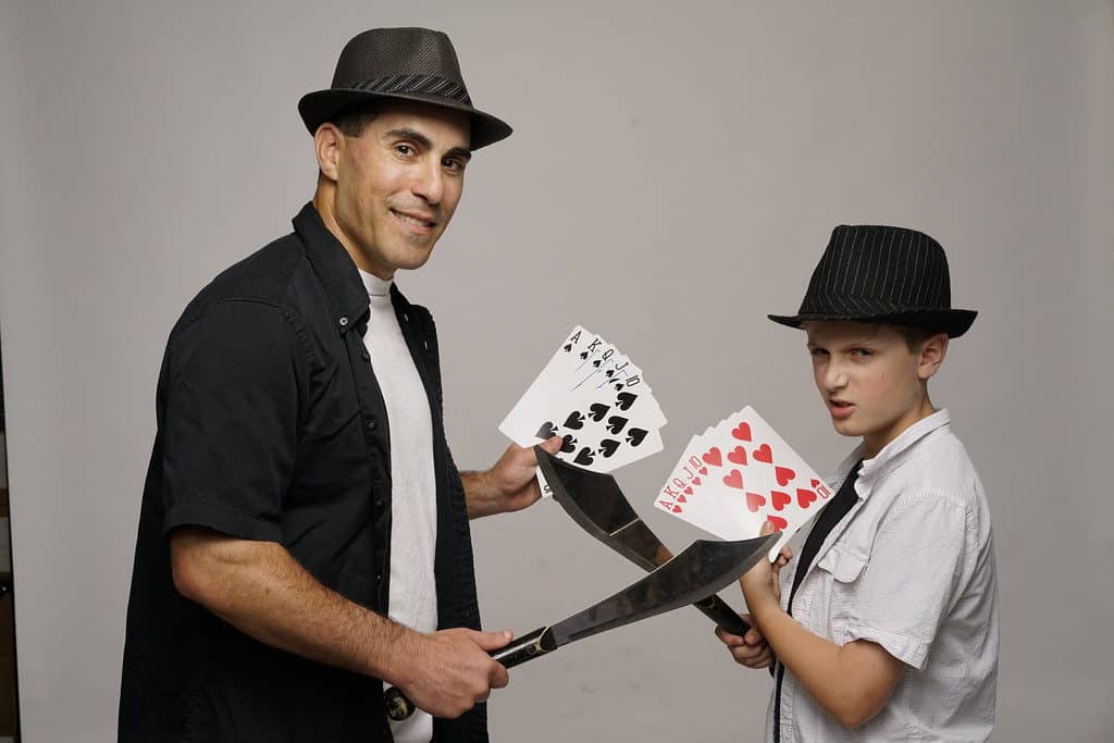 A man and woman holding playing cards in front of each other.