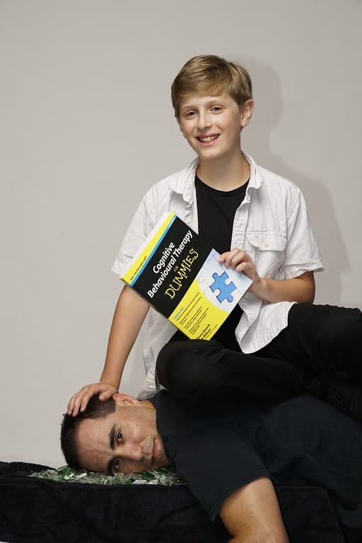 A boy and his father are posing for the camera.